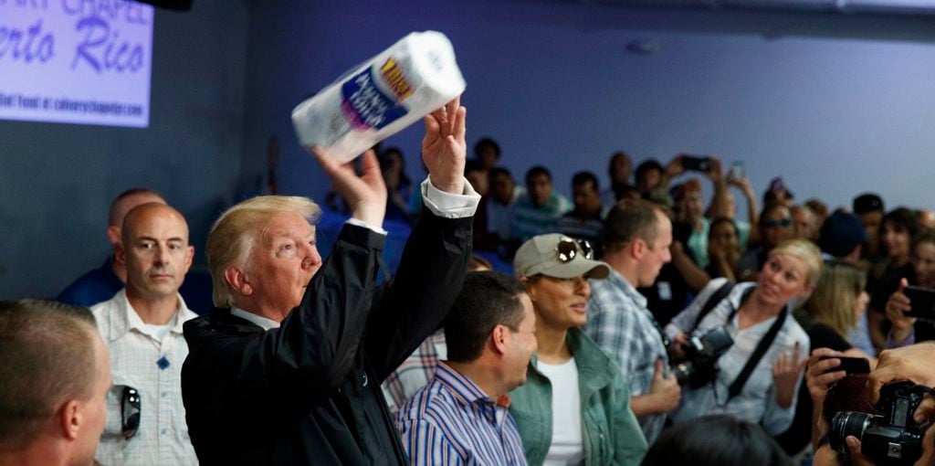 President Donald Trump tosses paper towels into a crowd as he hands out supplies at Calvary Chapel, Tuesday, Oct. 3, 2017, in Guaynabo, Puerto Rico. Trump is in Puerto Rico to survey hurricane damage. (AP Photo/Evan Vucci)