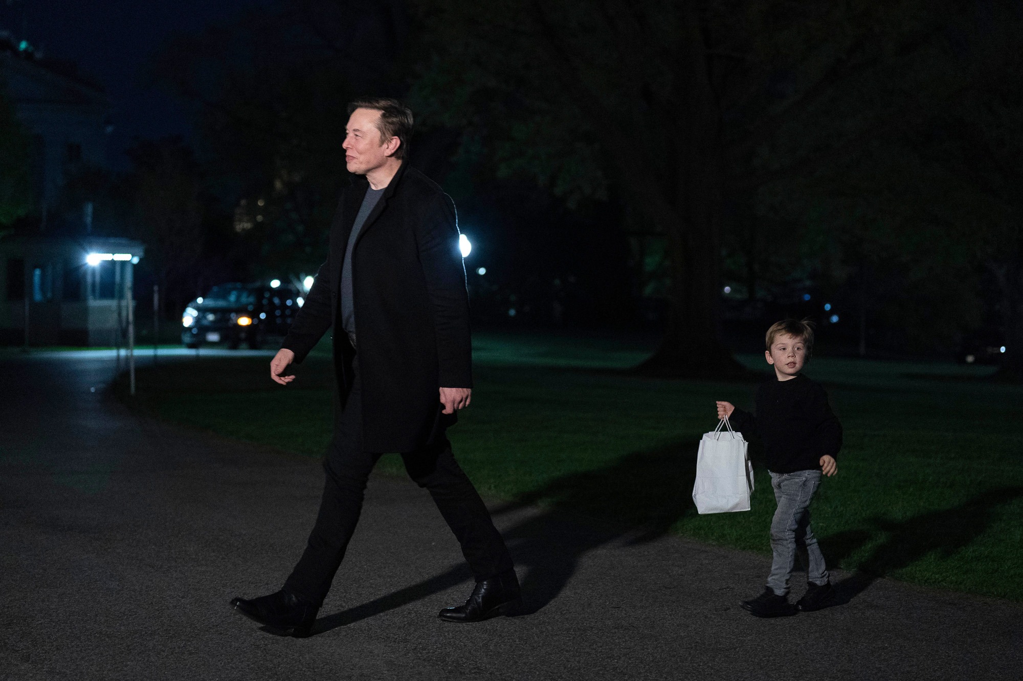 Elon Musk walks with his son at night on the White House grounds as scrutiny grows over the Department of Government Efficiency’s federal cost-cutting claims
