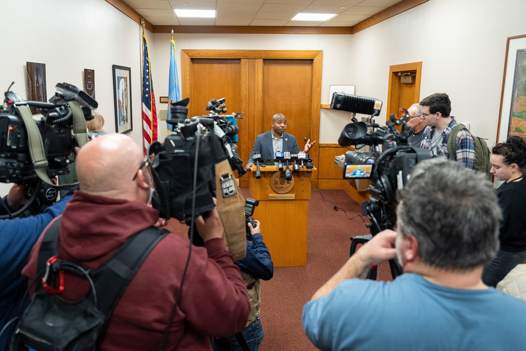 Milwaukee County official speaks at press conference following the arrest of Judge Hannah Dugan, surrounded by reporters and TV cameras