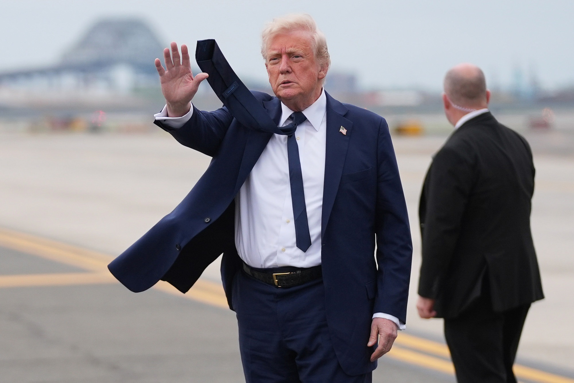 Donald Trump waves on airport tarmac during his second term, as approval ratings fall and controversy grows over economic and civil rights policies