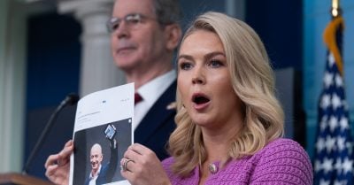 White House Press Secretary Karoline Leavitt holds a printed photo of Jeff Bezos while addressing the media about Amazon and tariff-related controversy.