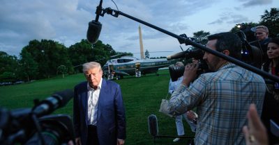 Donald Trump speaks to reporters on the White House lawn as Marine One sits in the background after returning from a trip.