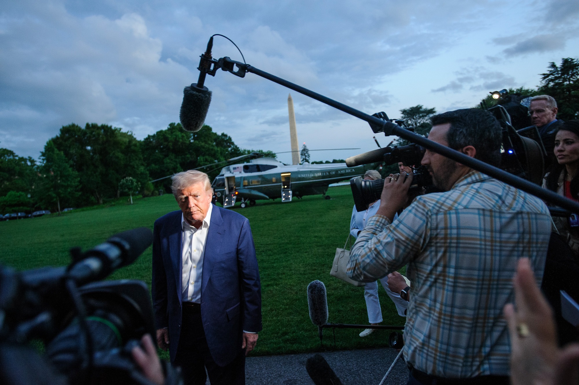 Donald Trump speaks to reporters on the White House lawn as Marine One sits in the background after returning from a trip.
