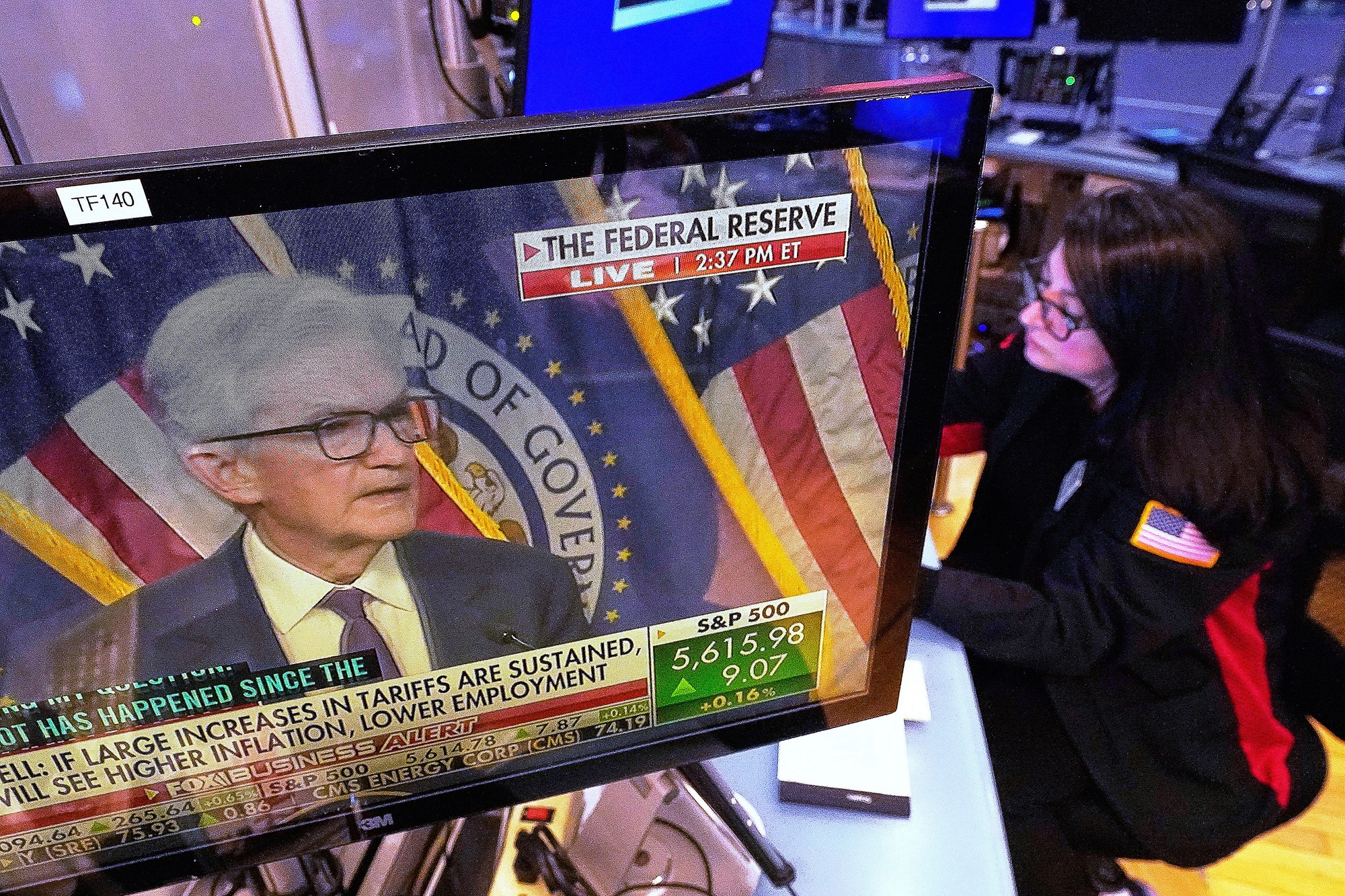 Federal Reserve Chair Jerome Powell appears on a TV screen as a trader works on the floor of the New York Stock Exchange during a press conference on interest rates.