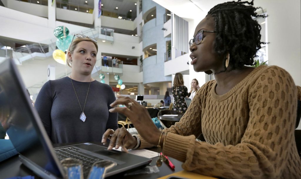 FILE - In this Tuesday, Jan. 24, 2017, file photo, Xonjenese Jacobs, right, helps Kristen Niemi sign up for the Affordable Care Act during a healthcare expo at the University of South Florida, in Tampa, Fla. The government must shell out billions of dollars if policymakers want to stabilize health insurance markets created by the Affordable Care Act. That’s the message insurers are delivering in July 2017 to a Republican-controlled Congress that is busy dismantling the Obama-era law and may be reluctant to continue propping it up with federal funds. (AP Photo/Chris O'Meara, File)