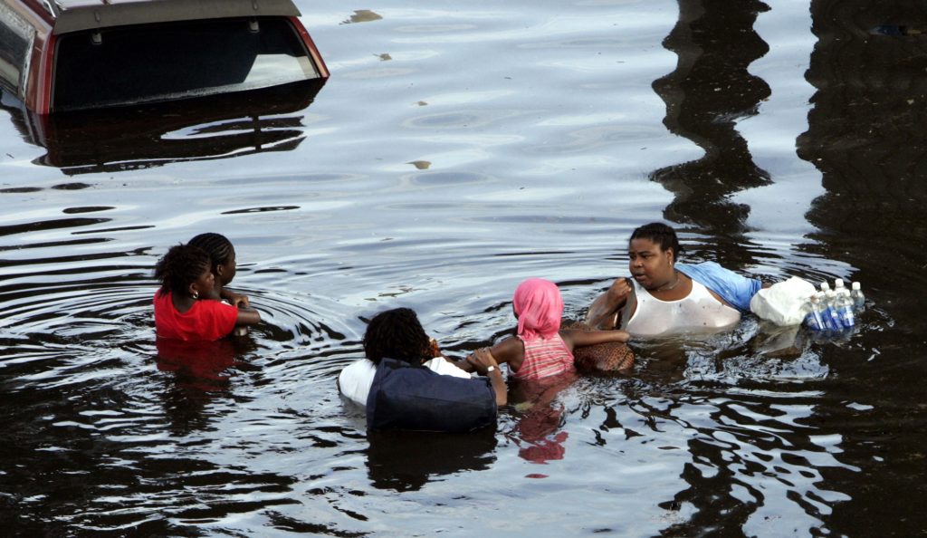 A New Orleans family tries to make their way through floodwaters in the downtown area of the Crescent City on Tuesday, Aug. 30, 2005. The water continues to rise after Hurricane Katrina pounded the area on Monday. (AP Photo/Bill Haber)