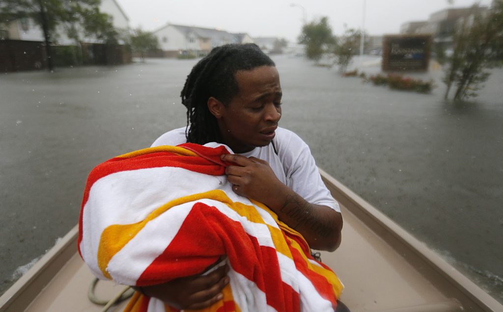 Demetres Fair holds a towel over his daughter Damouri Fair, 2, as they are rescued by boat by members of the Louisiana Department of Wildlife and Fisheries and the Houston Fire Department during flooding from Tropical Storm Harvey in Houston, Monday, Aug. 28, 2017. (AP Photo/Gerald Herbert)