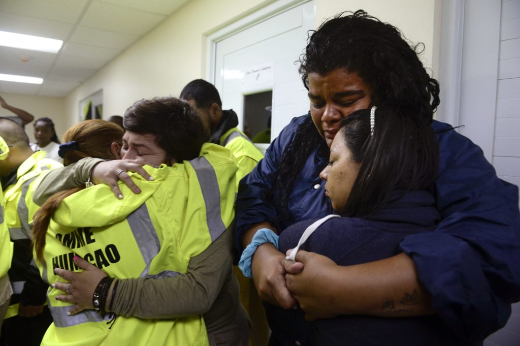 Rescue team members Candida Lozada, left, and Stephanie Rivera, second from left, Mary Rodriguez, second from right, and Zuly Ruiz, right, embrace as they wait to assist in the aftermath of Hurricane Maria in Humacao, Puerto Rico, Wednesday, Sept. 20, 2017. (AP Photo/Carlos Giusti)