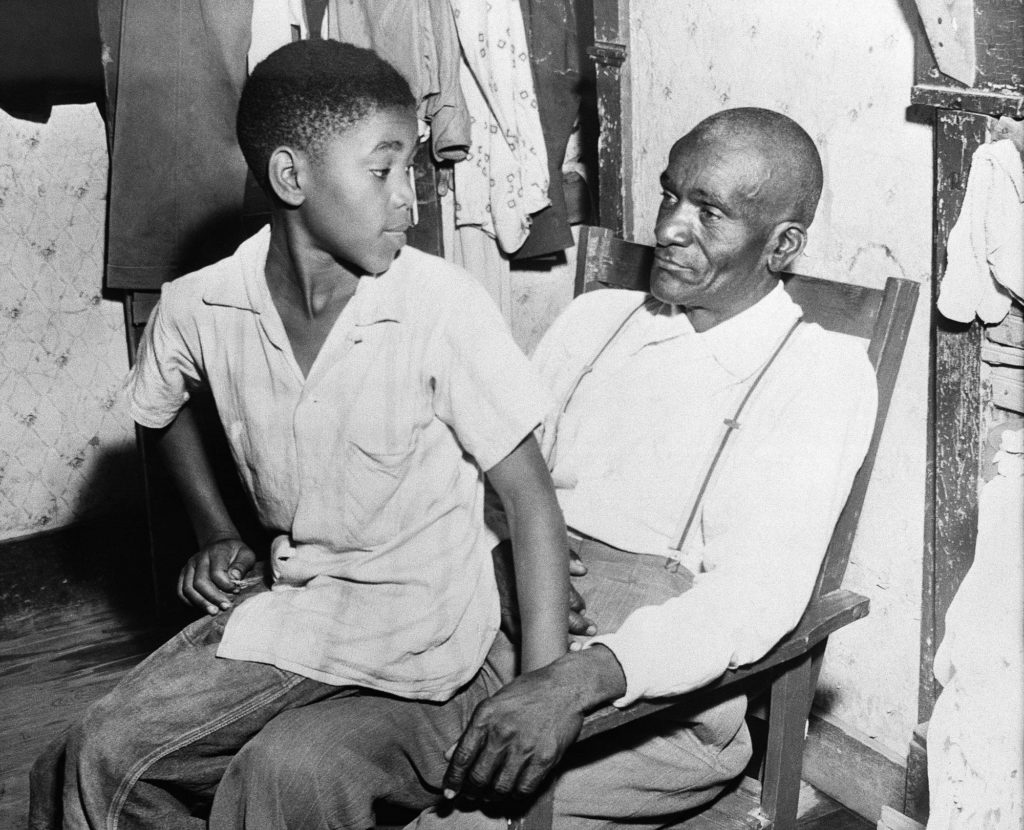 Mose Wright, right, and his son Simeon, sit in their home at the community of Money, Miss. , near Greenwood, and discuss the loss of their 15-year-old relative, Emmett Till, September 1, 1955. Till was a nephew of Mose Wright. Till's body was found in the Tallahatchie River August 31. He had a bullet hole in his head. Two white men are being held in jail at Greenwood in connection with the death. (AP Photo)