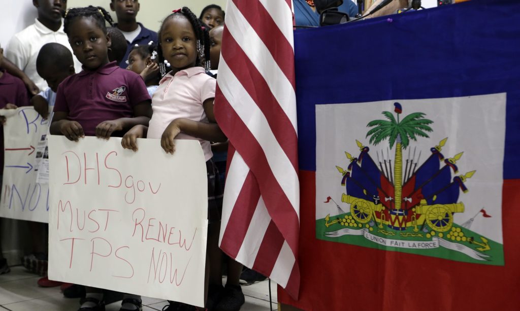 Children stand next to United States and Haitian flags as they hold signs in support of renewing Temporary Protected Status (TPS) for immigrants from Central America and Haiti now living in the United States, during a news conference Monday, Nov. 6, 2017, in Miami. The Department of Homeland Security is expected to rule soon on whether or not to renew the protected status. (AP Photo/Lynne Sladky)