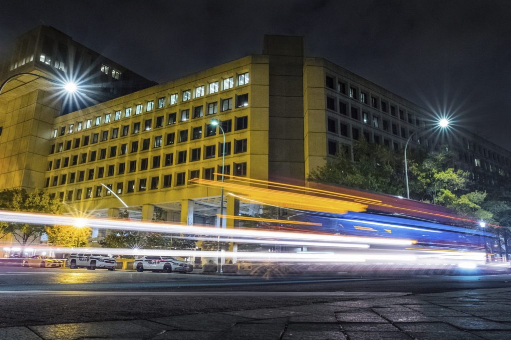 Traffic along Pennsylvania Avenue in Washington streaks past the Federal Bureau of Investigation headquarters building Wednesday night, Nov. 1, 2017. Scores of U.S. diplomatic, military and government figures were not told about attempts to hack into their emails even though the FBI knew they were in the Kremlin’s crosshairs, The Associated Press has learned. (AP Photo/J. David Ake)