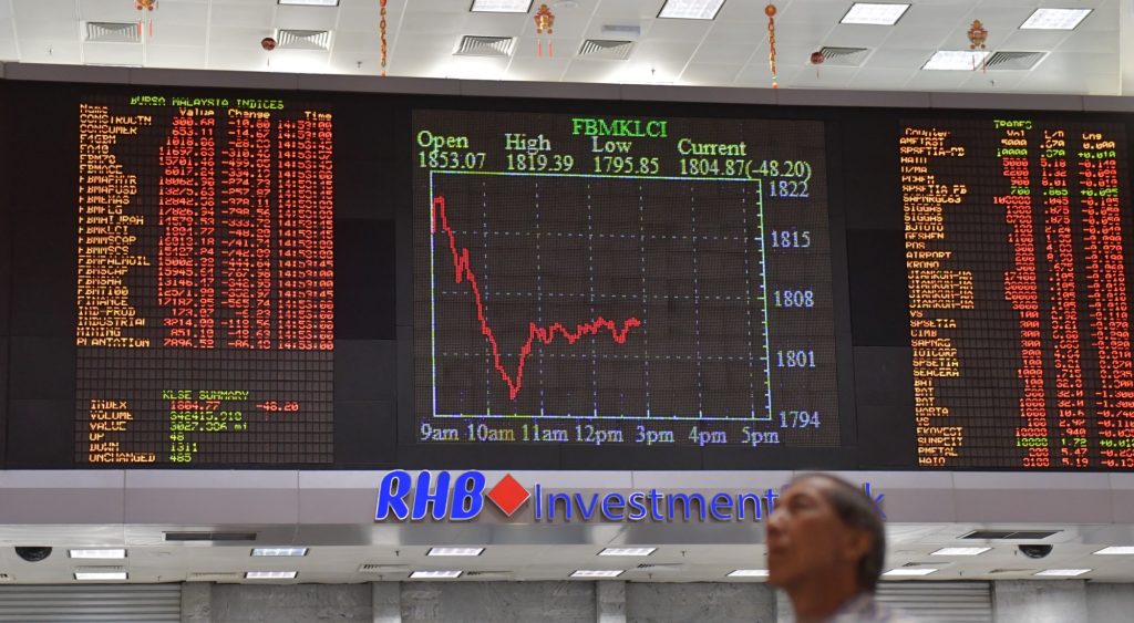 A Malaysian man watches trading boards at a private stock market gallery in Kuala Lumpur, Malaysia, Tuesday, Feb. 6, 2018. Asian markets were rattled Tuesday by the miseries on Wall Street, with Japan's Nikkei 225 index briefly dipping more than 7 percent, but investors seemed to be taking the gyrations in stride. (AP Photo/Vincent Thian)