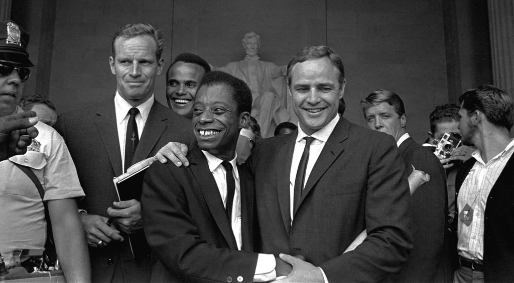 Actor Marlon Brando, right, poses with his arm around James Baldwin, author and civil rights leader, in front of the Lincoln statue at the Lincoln Memorial, August 28, 1963, during the March on Washington demonstration ceremonies which followed the mass parade.  Posing with them are actors Charlton Heston, left, and Harry Belafonte.  (AP Photo)