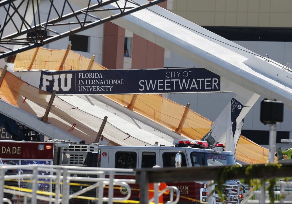A sign above the rubble of a new pedestrian bridge is shown after the bridge collapsed onto a highway at Florida International University in Miami on Thursday, March 15, 2018. The pedestrian bridge collapsed onto a highway crushing multiple vehicles and killing several people. (AP Photo/Wilfredo Lee)