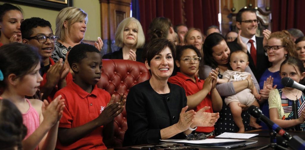 Iowa Gov. Kim Reynolds, center, reacts after signing a six-week abortion ban bill into law during a ceremony in her formal office, Friday, May 4, 2018, in Des Moines, Iowa. The bill gives Iowa the strictest abortion restrictions in the nation, setting the state up for a lengthy court challenge. (AP Photo/Charlie Neibergall)