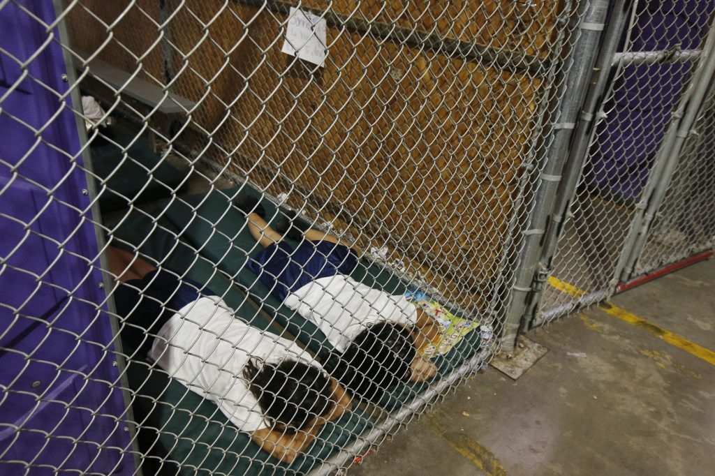 FILE - In this June 18, 2014 file photo, two female detainees sleep in a holding cell, as the children are separated by age group and gender, as hundreds of mostly Central American immigrant children are being processed and held at the U.S. Customs and Border Protection Nogales Placement Center in Nogales, Ariz. President Donald Trump has seized on an error by liberal activists for tweeting photos of detainees at the U.S.-Mexico border in steel cages and blamed the current administration for separating immigrant children from their parents. The photos were taken by The Associated Press in 2014, when President Barack Obama was in office. (AP Photo/Ross D. Franklin, Pool)