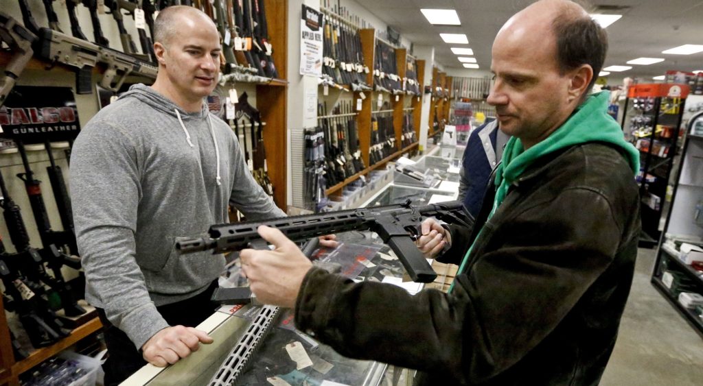 Wes Morosky, owner of Duke's Sport Shop. left, helps Ron Detka as he shops for a rifle on Friday, March 2, 2018, at his store in New Castle. Morosky said business has gone up recently, but that's thanks to the annual infusion of tax refund checks. Sales of firearms slowed dramatically after the election of President Donald Trump in 2016 allayed fears of a Democratic crackdown on gun owners. That trend continues, even with talk of gun control in Congress following the massacre of 17 people at a Florida high school last month. (AP Photo/Keith Srakocic)