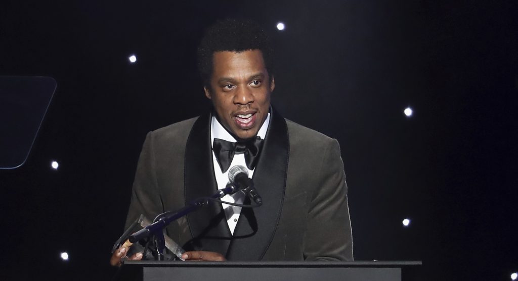 FILE - In this Jan. 27, 2018, file photo, honoree Jay-Z speaks onstage at the 2018 Pre-Grammy Gala And Salute To Industry Icons at the Sheraton New York Times Square Hotel in New York. Jay-Z must explain why he's dodging a subpoena rather than answering questions related to a financial investigation of a consumer brand company that bought his Rocawear clothing line, a judge says. In an order made public Thursday, May 3, U.S. District Judge Paul G. Gardephe instructed the performer and entrepreneur, whose birth name is Shawn Carter, to appear in a New York courtroom next Tuesday to explain himself. (Photo by Michael Zorn/Invision/AP, File)