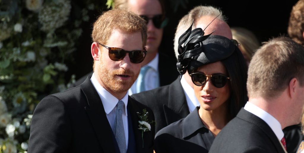 Britain's Prince Harry, left and Meghan, the Duchess of Sussex join guests outside St Mary the Virgin Church after attending the wedding of Charlie van Straubenzee and Daisy Jenks, in Frensham, England, Saturday Aug. 4, 2018. Aug. 4 marks the 37th birthday of the Duchess. (Yui Mok/PA via AP)