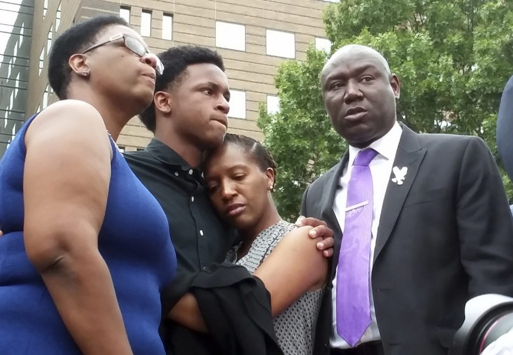 Brandt Jean, center left, brother of shooting victim Botham Jean, hugs his sister Allisa Charles-Findley, during a news conference outside the Frank Crowley Courts Building on Monday, Sept. 10, 2018, in Dallas, about the shooting of Botham Jean by Dallas police officer Amber Guyger on Thursday. He was joined by his mother, Allison Jean, left, and attorney Benjamin Crump, right. (AP Photo/Ryan Tarinelli)