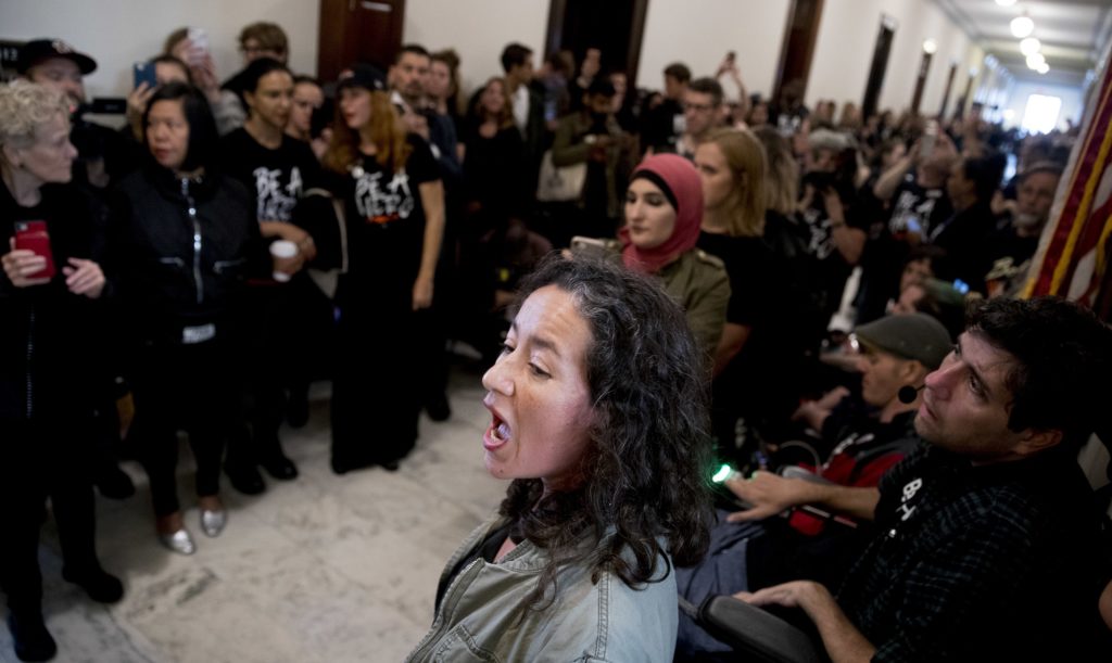 Ana Maria Archila of New York, N.Y., tells a personal story to protesters against Supreme Court nominee Brett Kavanaugh gathered outside offices of Sen. Jeff Flake, R-Ariz., on Capitol Hill in Washington, Monday, Sept. 24, 2018, as the Senate begins a week of scrutiny of President Donald Trump's nominee to the high court. Judge Brett Kavanaugh's nomination to the U.S. Supreme Court has been further imperiled by a second sexual-misconduct allegation, dating to his first year at Yale University. (AP Photo/Andrew Harnik)