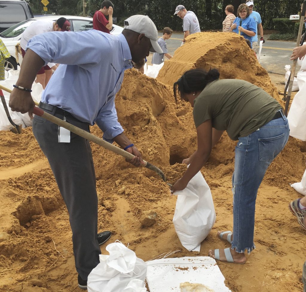 Tallahassee Mayor and Democratic gubernatorial candidate, Andrew Gillum, left, helps Eboni Sipling fill up sandbags in Tallahassee, Fla., Monday, Oct. 8, 2018. Residents in Florida's Panhandle and Big Bend are getting ready for Hurricane Michael, which is expected to make landfall by midweek. (AP Photo/Gary Fineout)