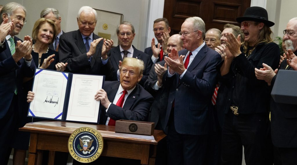 President Donald Trump shows the "Orrin G. Hatch-Bob Goodlatte Music Modernization Act," after signing it in the Roosevelt Room of the White House, Thursday, Oct. 11, 2018, in Washington. Second from right is musician Kid Rock. (AP Photo/Evan Vucci)