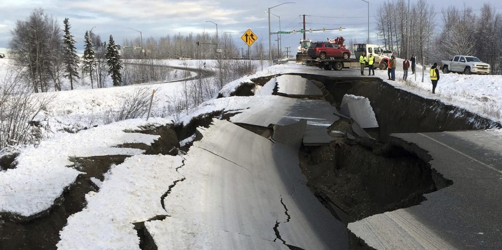 A tow truck holds a car that was pulled from on an off-ramp that collapsed during a morning earthquake on Friday, Nov. 30, 2018, in Anchorage, Alaska. The driver was not injured attempting to exit Minnesota Drive at International Airport Road. Back-to-back earthquakes measuring 7.0 and 5.8 rocked buildings and buckled roads Friday morning in Anchorage, prompting people to run from their offices or seek shelter under office desks, while a tsunami warning had some seeking higher ground. (AP Photo/Mike Dinneen)