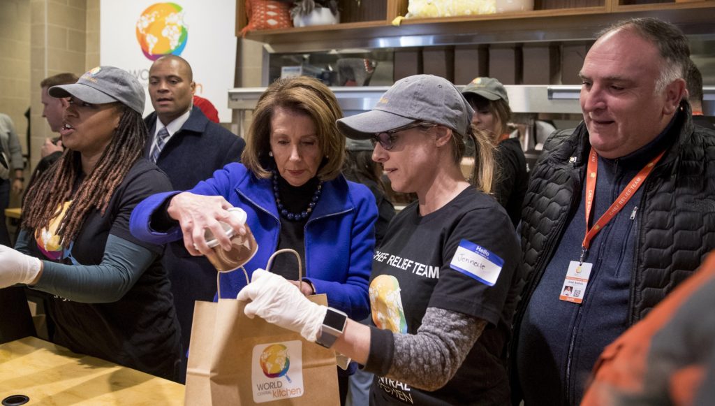 House Speaker Nancy Pelosi of Calif., center left, and Chef Jose Andres, right, help give out food at World Central Kitchen, the not-for-profit organization started by Chef Jose Andres, Tuesday, Jan. 22, 2019, in Washington. The organization devoted to providing meals in the wake of natural disasters, has set up a distribution center just blocks from the U.S. Capitol building to assist those affected by the government shutdown. (AP Photo/Andrew Harnik)