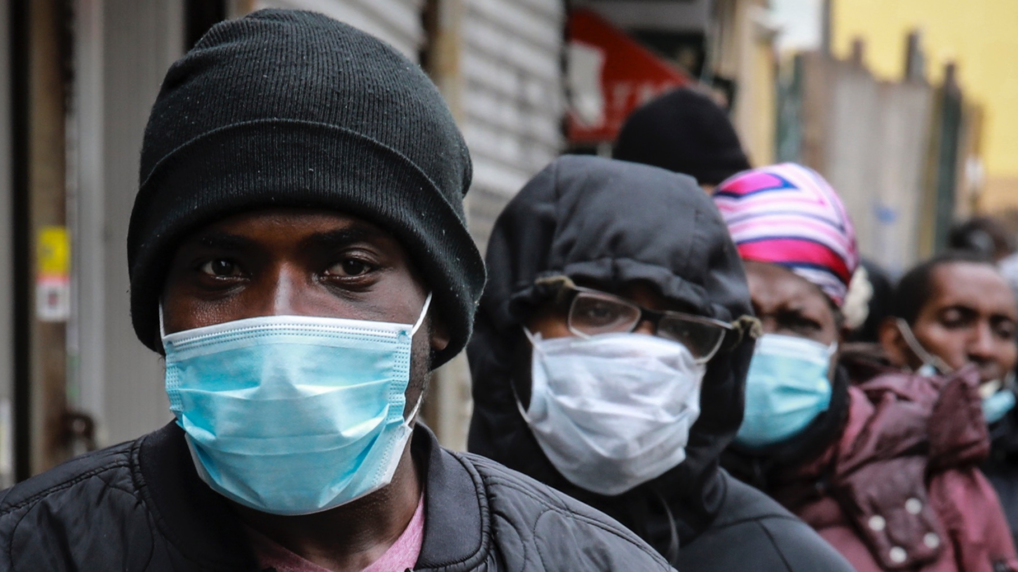 People wait for a distribution of masks and food from the Rev. Al Sharpton in the Harlem neighborhood of New York, after a new state mandate was issued requiring residents to wear face coverings in public due to the COVID-19 coronavirus, Saturday, April 18, 2020. "Inner-city residents must follow this mandate to ensure public health and safety," said Sharpton. The latest Associated Press analysis of available data shows that nearly one-third of those who have died from the coronavirus are African American, even though blacks are only about 14% of the population. (AP Photo/Bebeto Matthews)