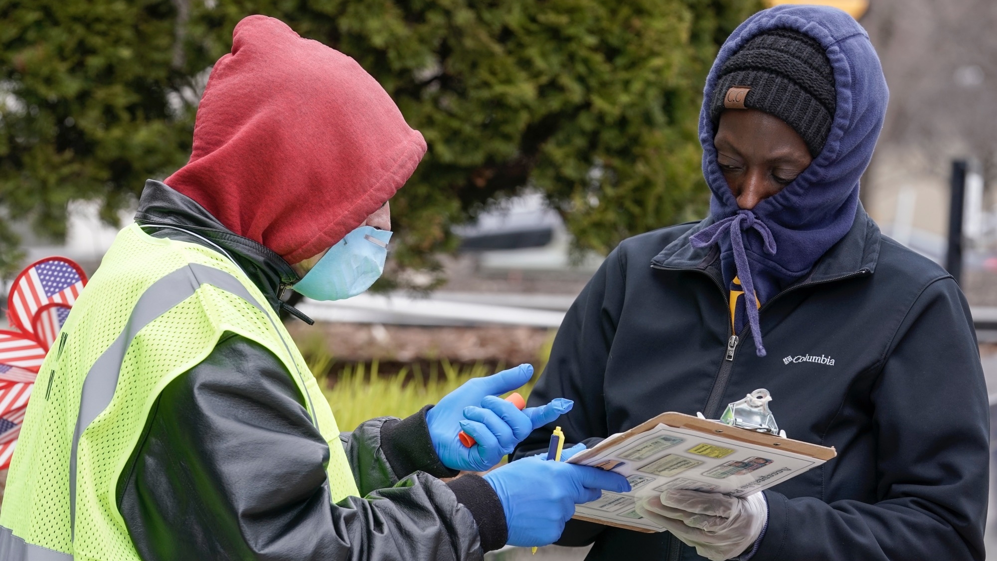 A worker helps voter outside the Frank P. Zeidler Municipal Building Monday March 30, 2020, in Milwaukee. The city is now allowing drive up early voting for the state's April 7 election. (AP Photo/Morry Gash)