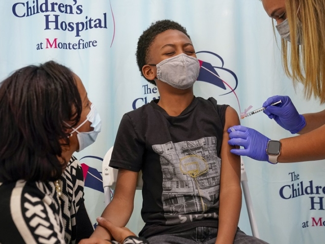 Dr. Rhonda Achonolu comforts her son Kenechi, 9, as he is inoculated with first dose of the Pfizer-BioNTech COVID-19 vaccine for children five to 12 years at The Children's Hospital at Montefiore, Wednesday, Nov. 3, 2021, in the Bronx borough of New York. The U.S. enters a new phase Wednesday in its COVID-19 vaccination campaign, with shots now available to millions of elementary-age children in what health officials hailed as a major breakthrough after more than 18 months of illness, hospitalizations, deaths and disrupted education. (AP Photo/Mary Altaffer)