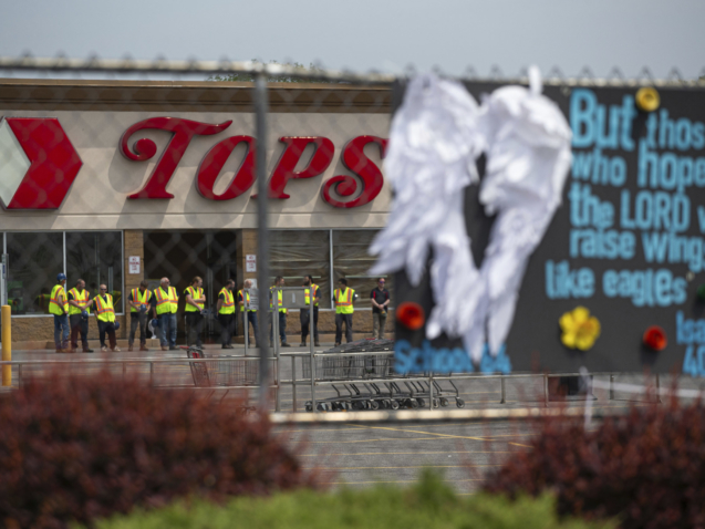 Investigators stand outside during a moment of silence for the victims of the Buffalo supermarket shooting outside the Tops Friendly Market on Saturday, May 21, 2022, in Buffalo, N.Y.  Tops was encouraging people to join its stores in a moment of silence to honor the shooting victims Saturday at 2:30 p.m., the approximate time of the attack a week earlier. Buffalo Mayor Byron Brown also called for 123 seconds of silence from 2:28 p.m. to 2:31 p.m., followed by the ringing of church bells 13 times throughout the city to honor the 10 people killed and three wounded. (AP Photo/Joshua Bessex)