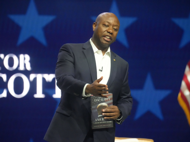 U.S. Sen. Tim Scott, R-S.C., holds a copy of his latest book, "America: A Redemption Story," as he gestures to his mother during a launch event at Seacoast Church on Saturday, Aug. 6, 2022, in Mount Pleasant, S.C. Scott, currently seeking what he has said will be his final U.S. Senate term, has been mentioned as a possible GOP presidential candidate in 2024. (AP Photo/Meg Kinnard)