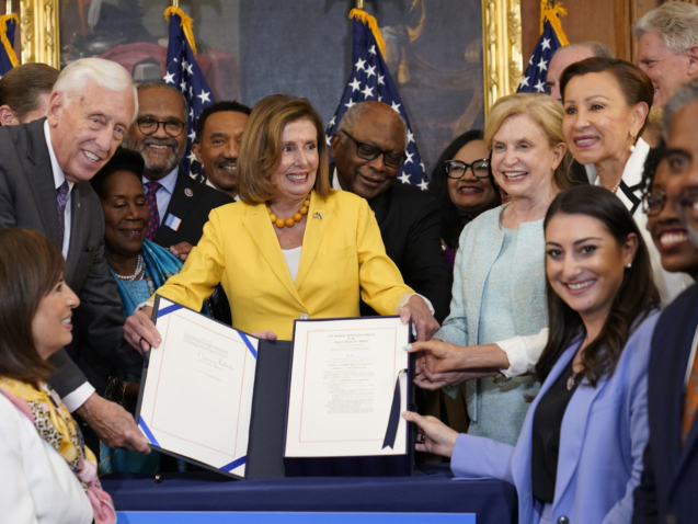 House Speaker Nancy Pelosi of Calif., surrounded by House Democrats, stands up after signing the Inflation Reduction Act of 2022 during a bill enrollment ceremony on Capitol Hill in Washington, Friday, Aug. 12, 2022. (AP Photo/Susan Walsh)