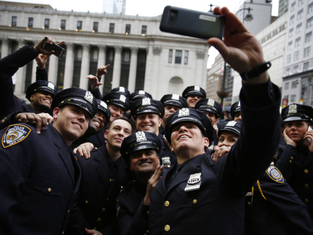 New NYPD Police Academy graduate Frank Cinturati, front, takes a selfie with his company after their graduation ceremony at Madison Square Garden in New York, Wednesday, Dec. 28, 2016. The ceremony celebrated 555 new officers who just completed their 6 months training. (AP Photo/Seth Wenig)