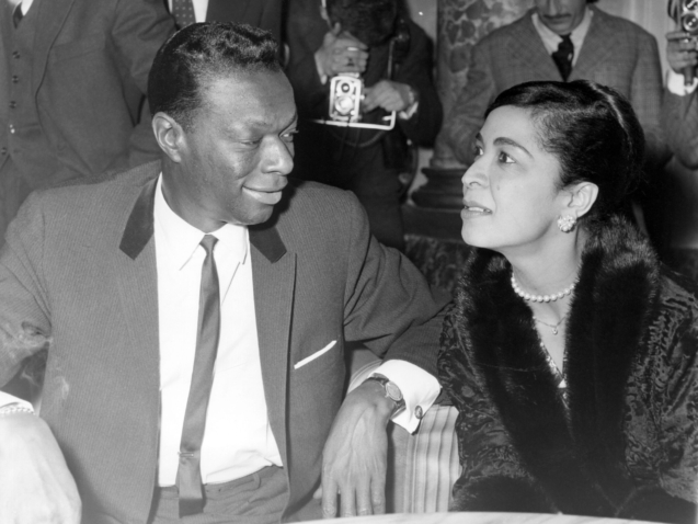 Famed American jazz singer Nat King Cole smilingly watches his wife, Maria Hawkins, as she tries to catch the sense of a question asked by a newsman, during a cocktail party and press conference in a Rome hotel on May 7, 1960. Cole and his wife arrived here earlier in the day and will give two concerts in Rome. (AP Photo/Jim Pringle)