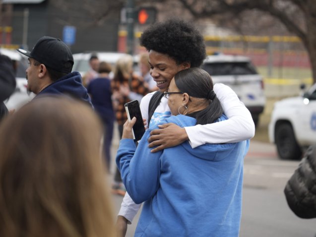 A student, rear, hugs a woman as they reunite following a shooting at East High School, Wednesday, March 22, 2023, in Denver. Authorities say two school administrators were shot and wounded after a handgun was found during a daily search of a student at the Denver high school. (AP Photo/David Zalubowski)