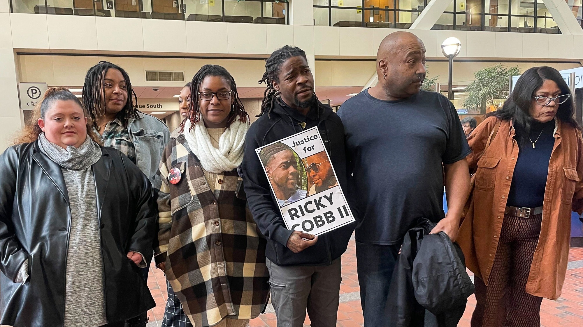 Family and activists for Ricky Cobb II, who was fatally shot by a Minnesota state trooper in a July 2023 traffic stop, stand with a sign that shows photos of Cobb and says "Justice for Ricky Cobb II" inside Hennepin County Government Center in Minneapolis, Minn., on Thursday, Jan. 25, 2024. (AP Photo/Trisha Ahmed)