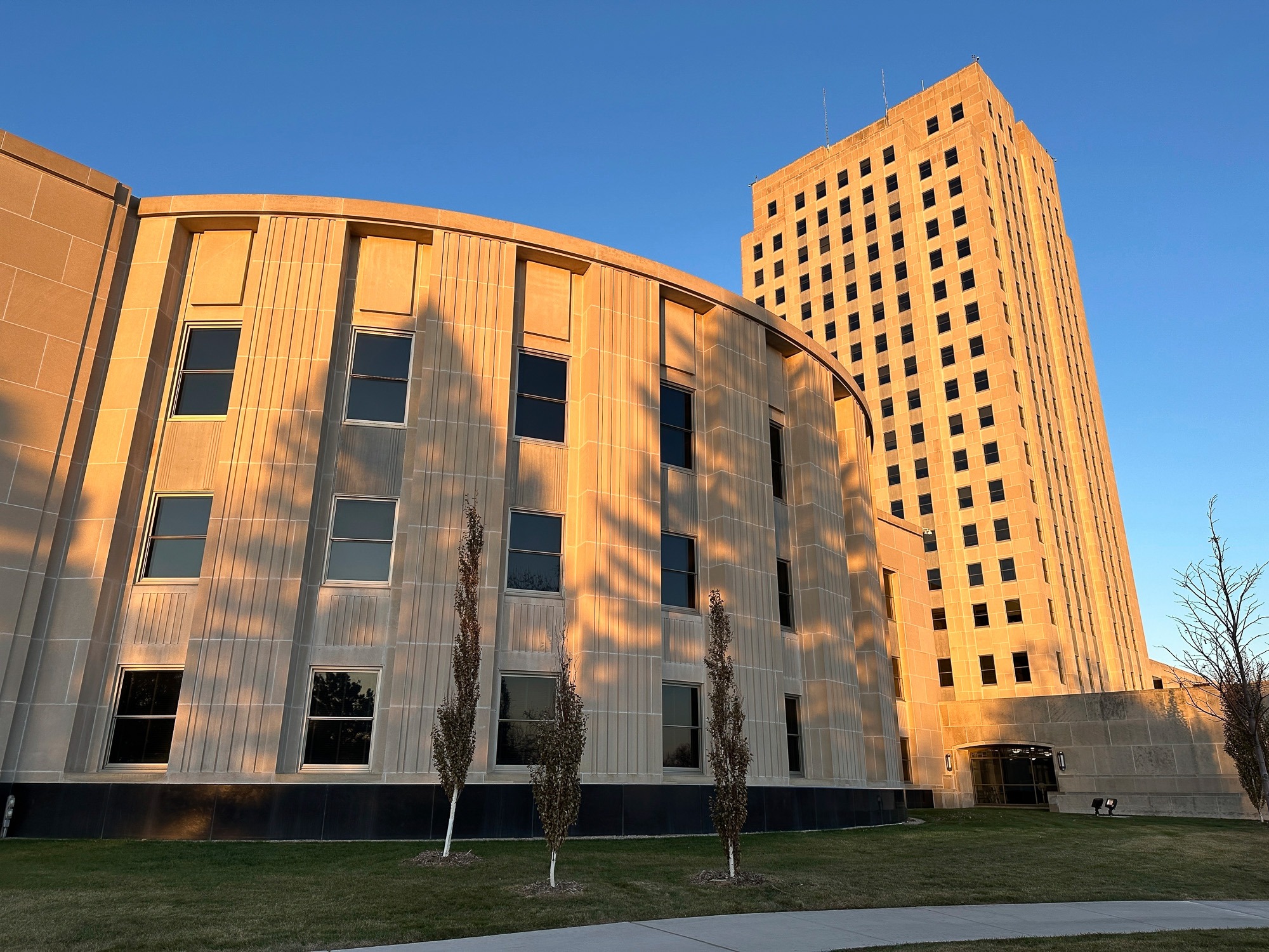 Sunlight illuminates the exterior of the North Dakota House of Representatives and the state Capitol tower in Bismarck, N.D.