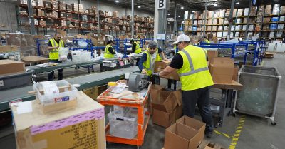 Trump economy faces racial disparities in jobs and wages as warehouse workers pack boxes in 2025.