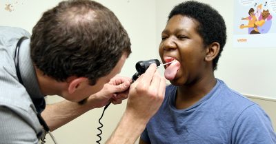 A pediatrician examines a young Black patient during a routine checkup at a community health clinic.