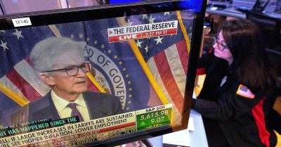 Federal Reserve Chair Jerome Powell appears on a TV screen as a trader works on the floor of the New York Stock Exchange during a press conference on interest rates.