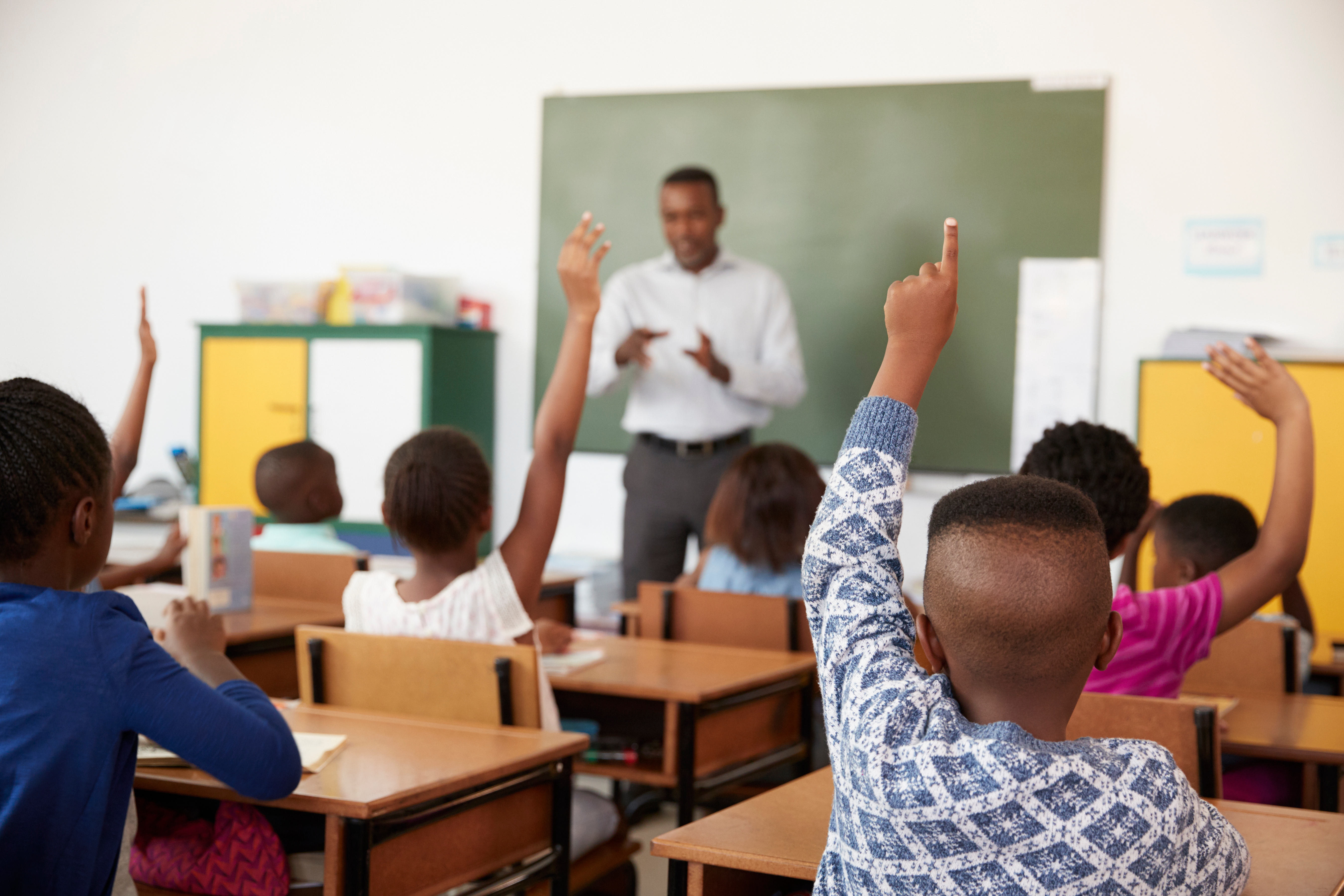 Kids raising hands during a lesson at an elementary school